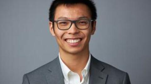 Man wearing a suit smiling into the camerea