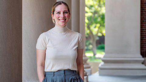 Woman standing in front of a column and smiling.